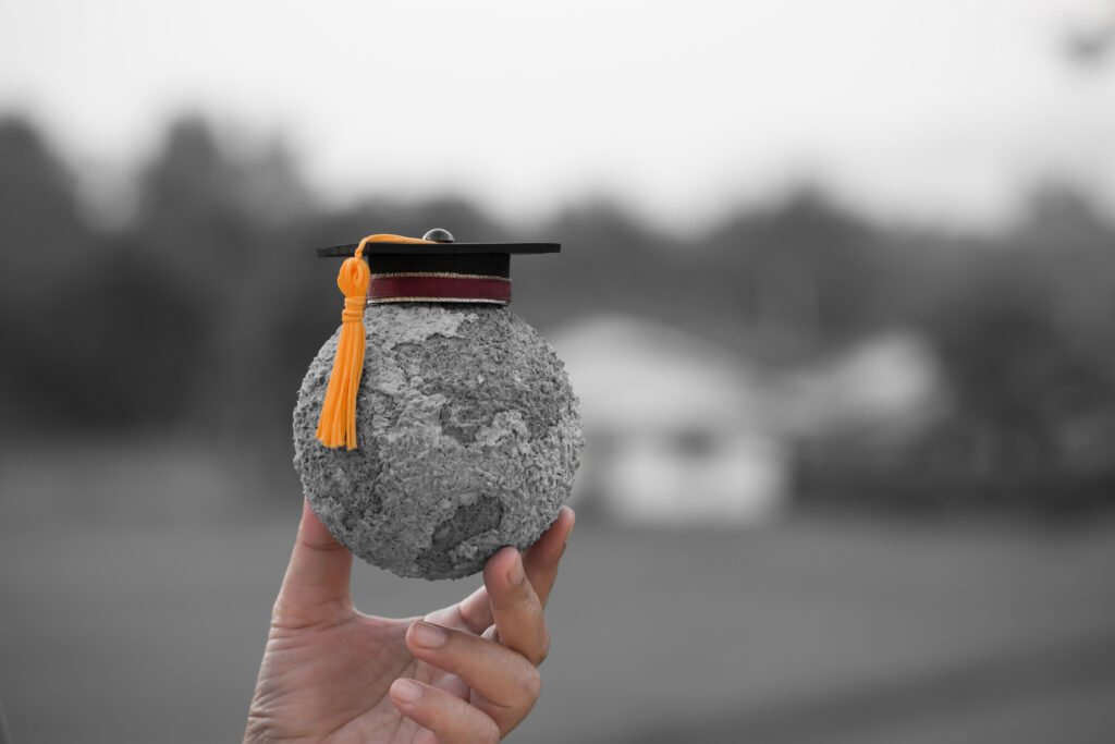 photo of a person holding a globe with a graduation cap on top