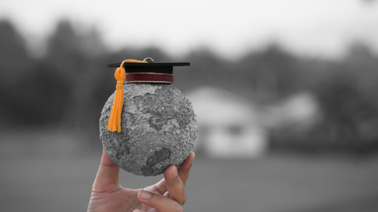 photo of a person holding a globe with a graduation cap on top