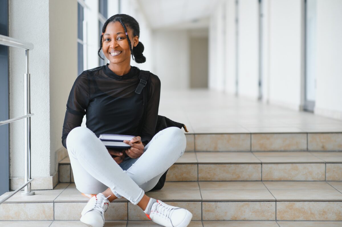 photo of a college student sitting on steps, smiling at camera