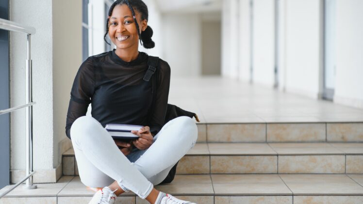 photo of a college student sitting on steps, smiling at camera